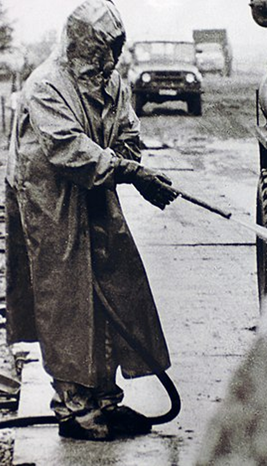 Persona con una manguera vestida con un traje nuclear.